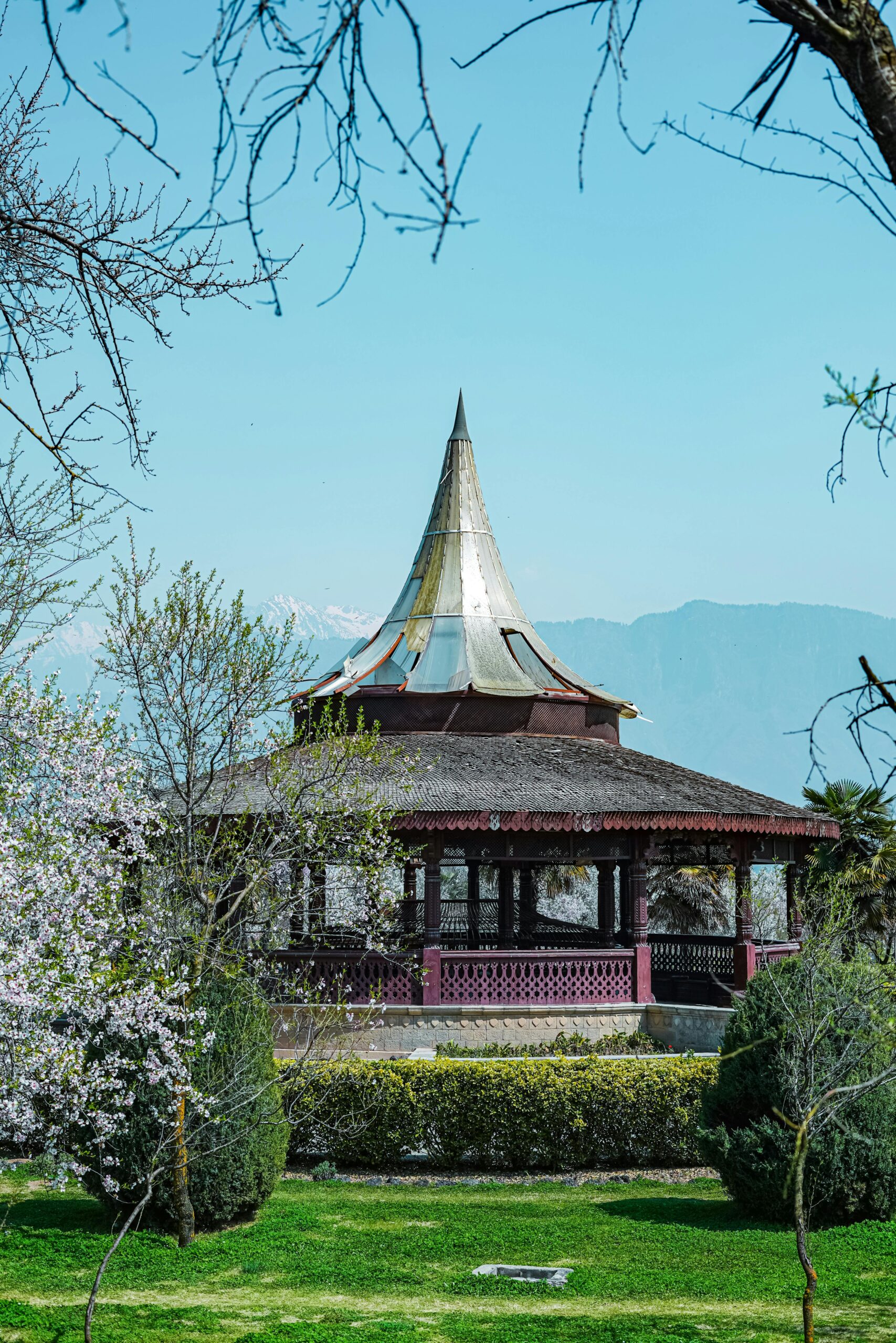 A beautiful gazebo in Badamwari Garden, Srinagar, with mountains and clear blue sky in the background.